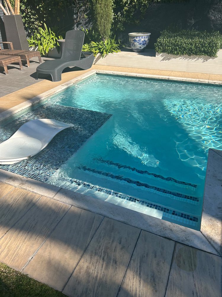 Piscina terminada con deck de madera y zona de descanso